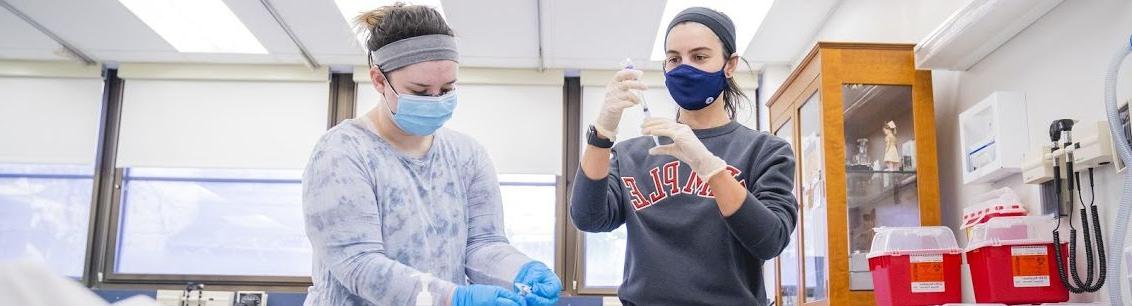 A pair of Temple student nurses working in a faux professional setting.